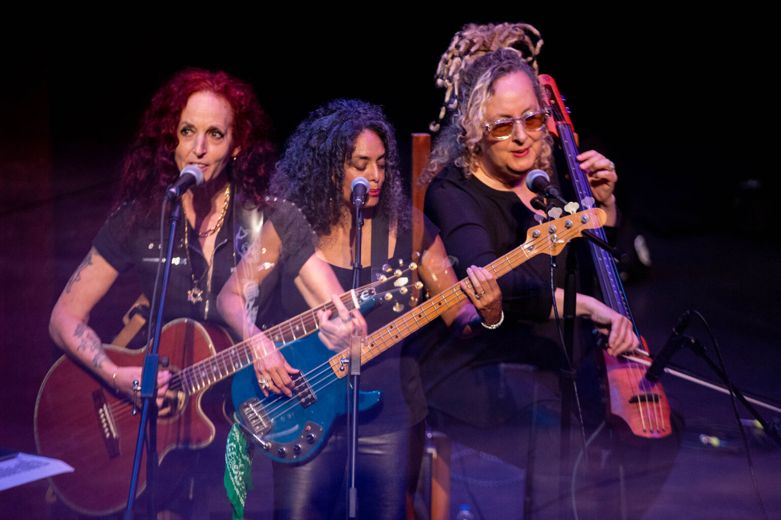 three women playing instruments on stage.