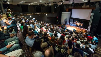 full crowd in theater seating during intermission.