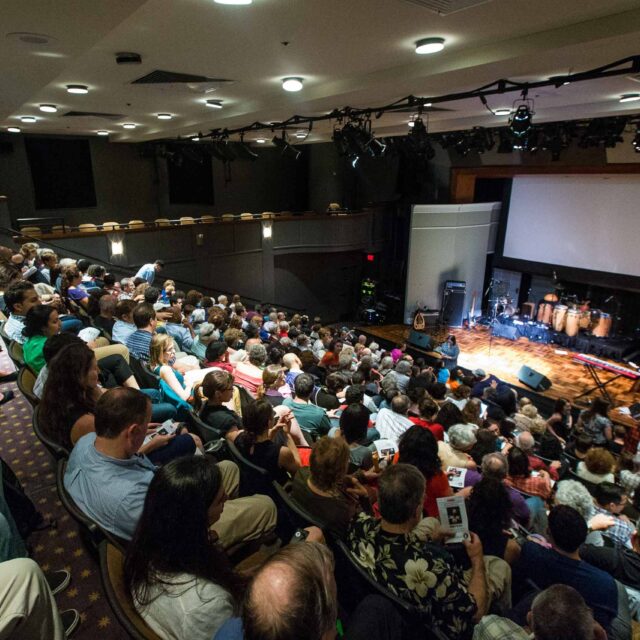 full crowd in theater seating during intermission.