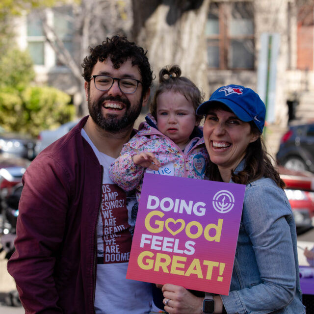 parents holding daughter and sign that says doing good feels great.