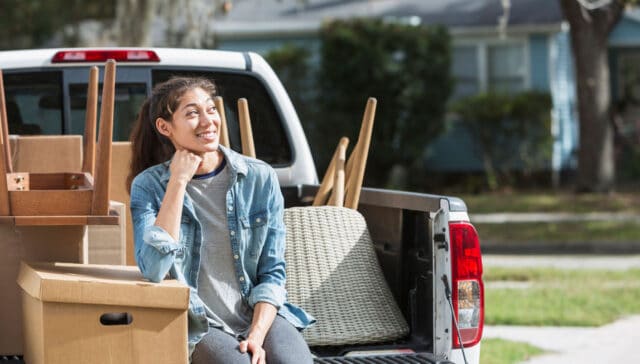 Woman sitting in pickup truck with moving boxes