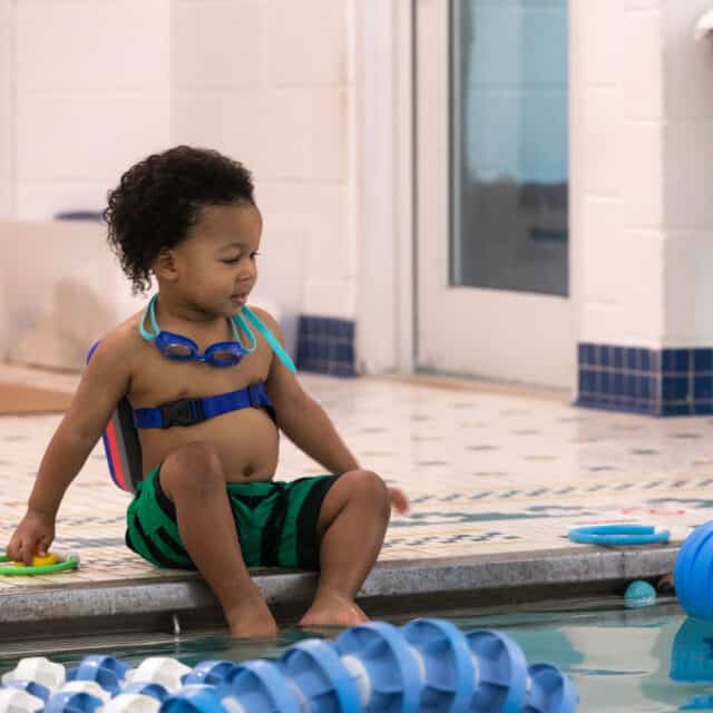 boy sitting on the edge of a swimming pool.