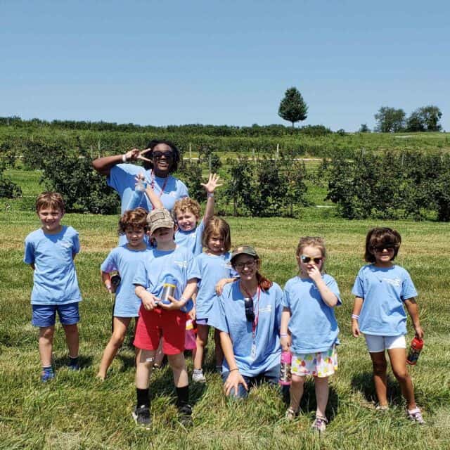 camp kids outside in a field with counselors.