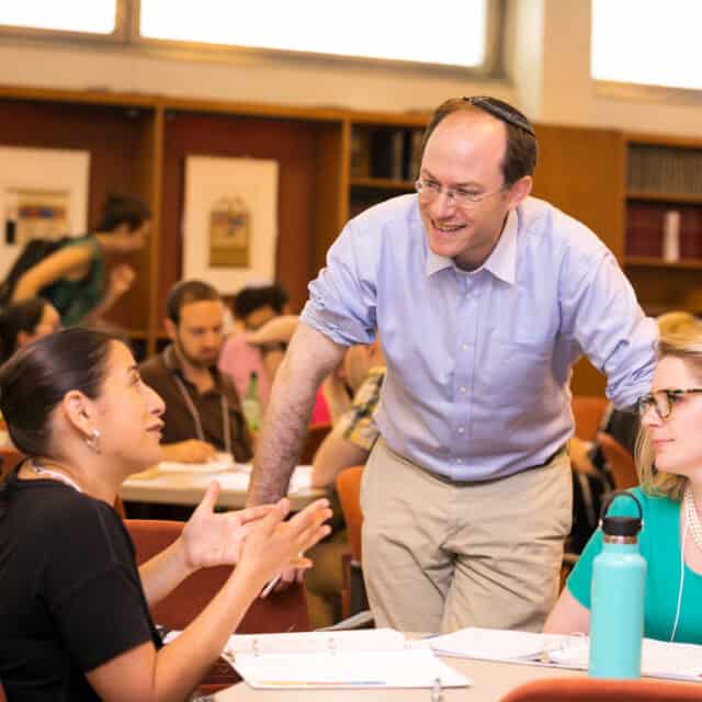 man talking to two women at table.