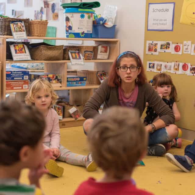 teacher teaching class of young children.