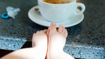 Cup of coffee with baby feet in foreground