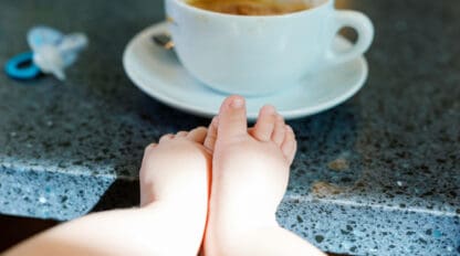 Cup of coffee with baby feet in foreground