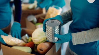 Closeup of people packing canned goods into donation box