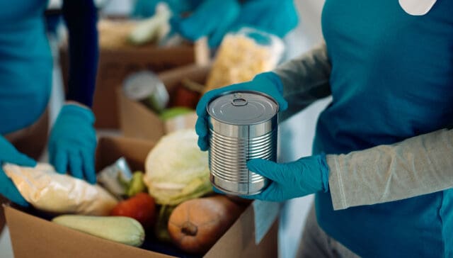 Closeup of people packing canned goods into donation box