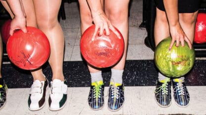 three people holding bowling balls