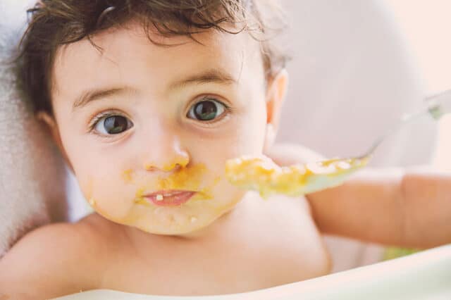 Baby eating pureed food with a spoon