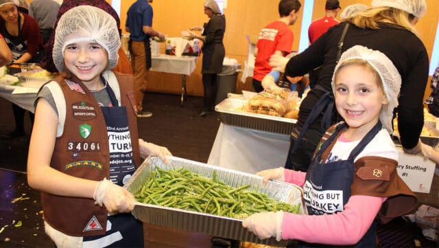 Young Children holding catering pan with green beans