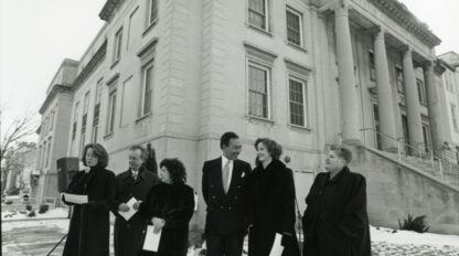 Black and white photo of six people in dark coats standing at the front corner of the EDCJCC. Photo is from the late 1990s.