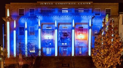 Photo of a menorah light projection across the front of the Edlavitch DCJCC building.